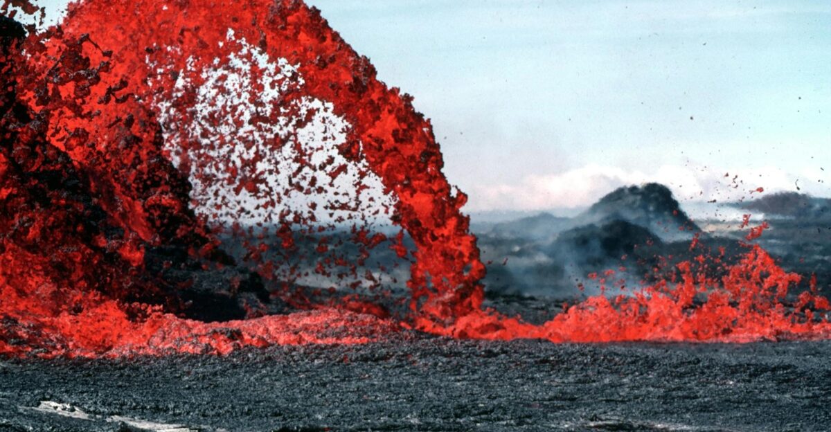 Stunning image of vibrant red lava flowing during a volcanic eruption in a rugged landscape