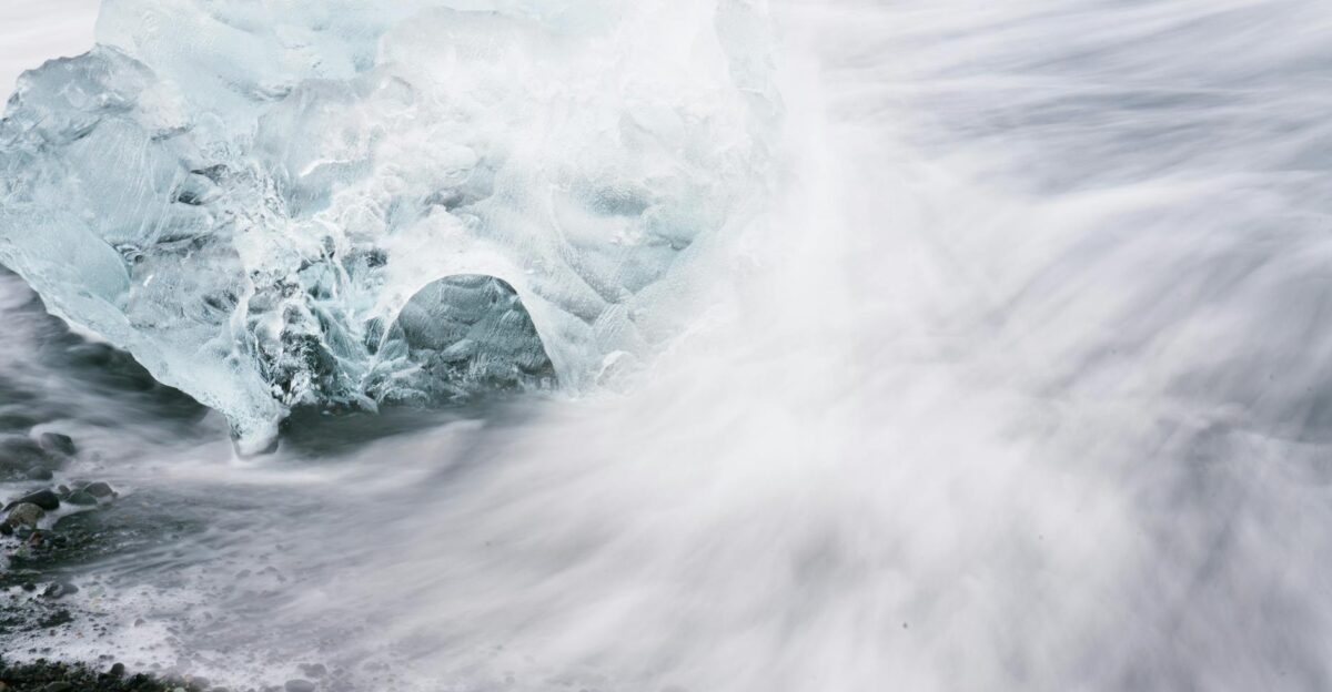 A dramatic ice block meets ocean waves on a rocky coast showcasing nature s power