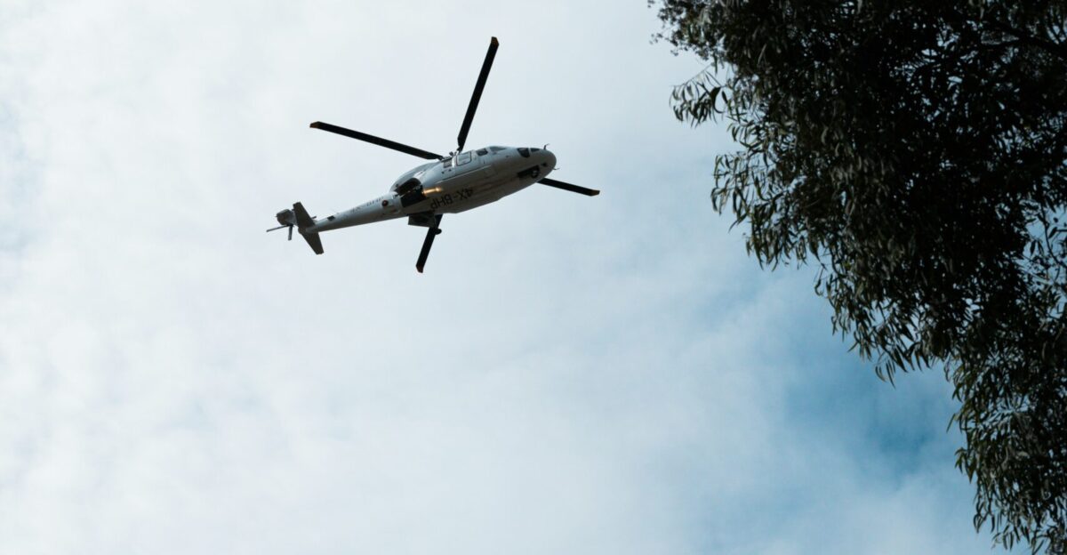 a helicopter flying through a cloudy blue sky
