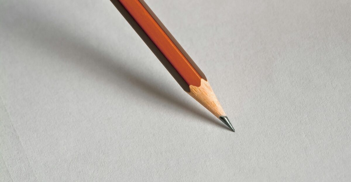 Detailed close-up of a wooden pencil resting on white paper perfect for educational themes