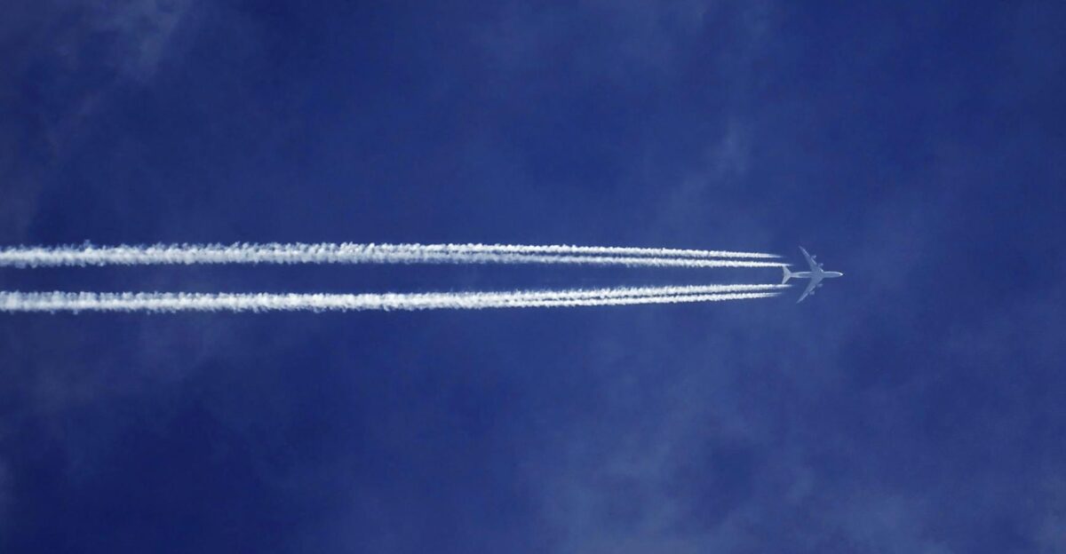 A jet airplane leaves contrails in a clear blue sky symbolizing speed and modern aviation