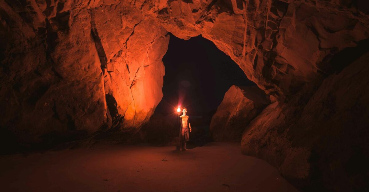 A lone adventurer illuminates a vast Californian cave with a torch at night