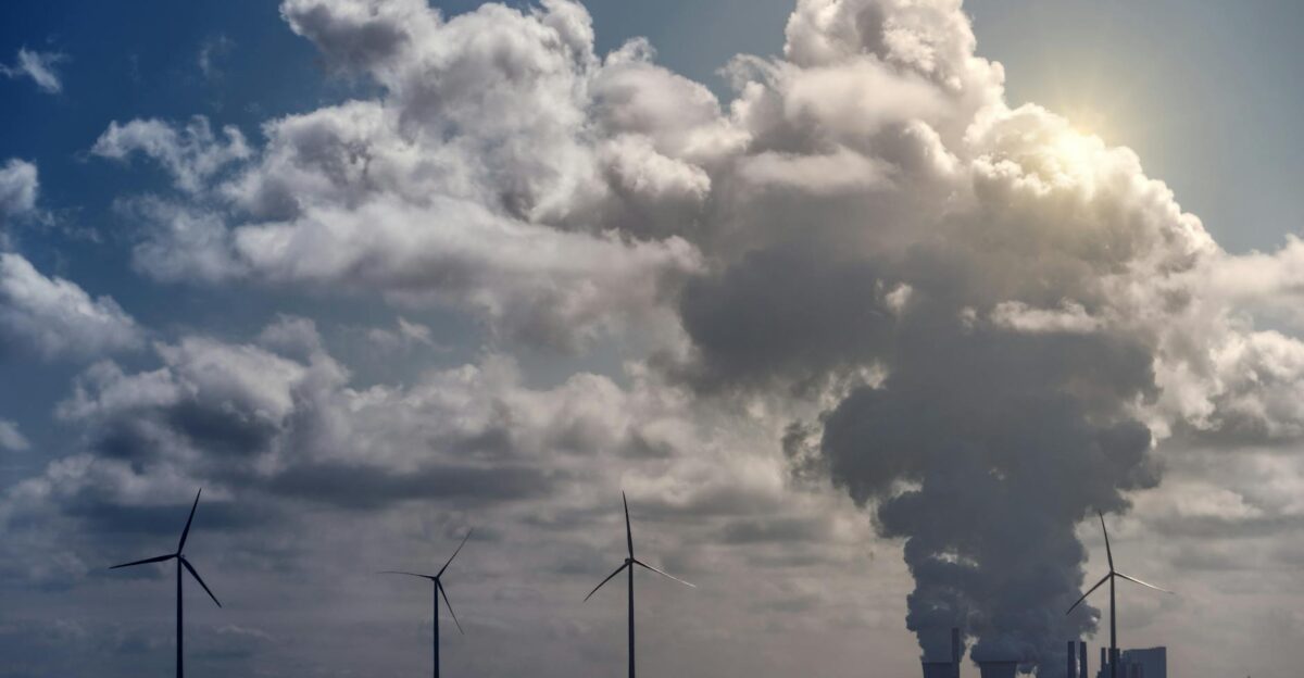 Wind turbines and a power plant under dramatic cumulus clouds in a rural landscape