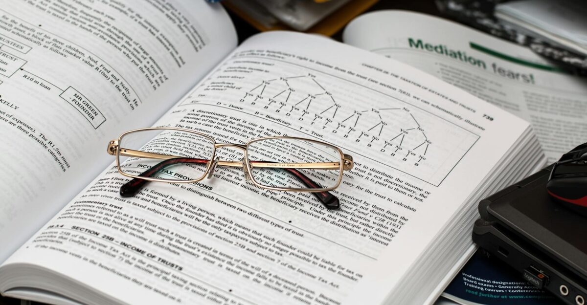 An open book with reading glasses surrounded by study materials and a laptop ideal for education themes