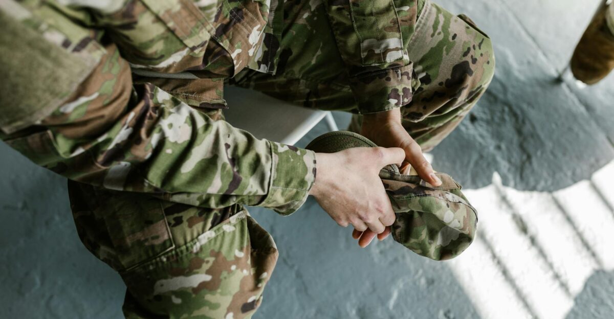 Soldier adjusting combat boots focused on military uniform in daylight