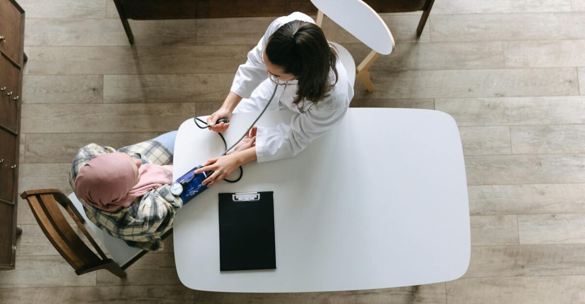 Overhead view of a doctor checking a patient s blood pressure during a healthcare consultation indoors