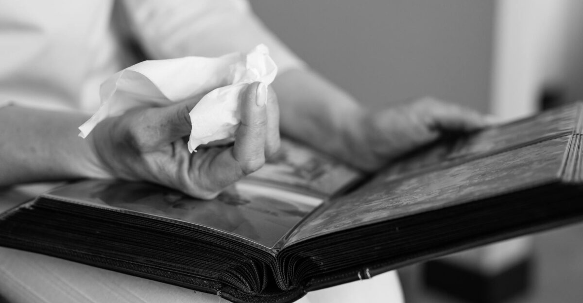 Close-up of hands holding a photo album and tissue evoking memories