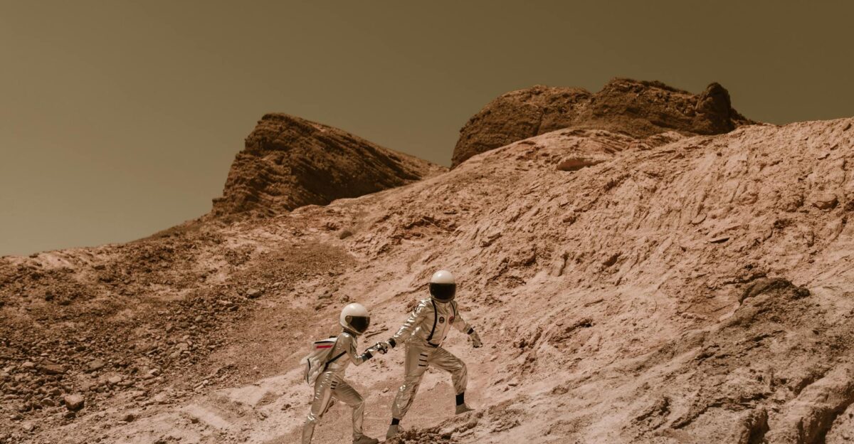 Two astronauts exploring a barren alien landscape resembling Mars