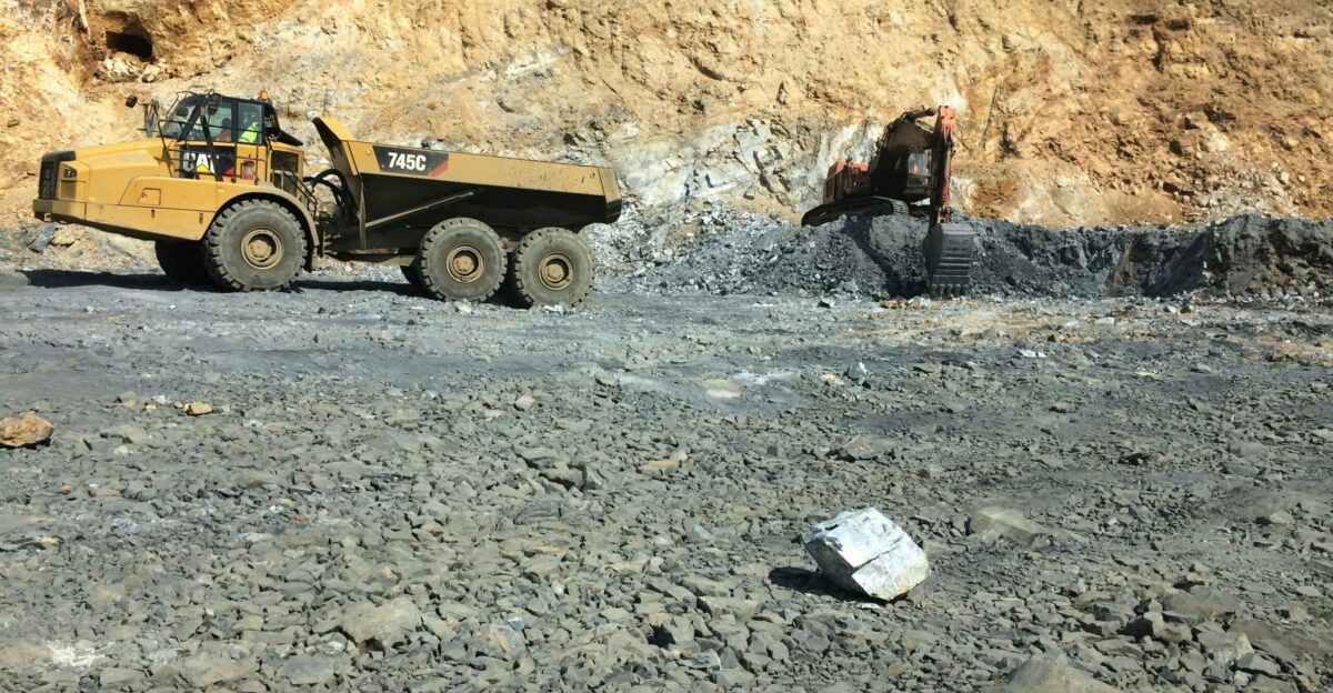 yellow heavy equipment filled with stone by back-hoe
