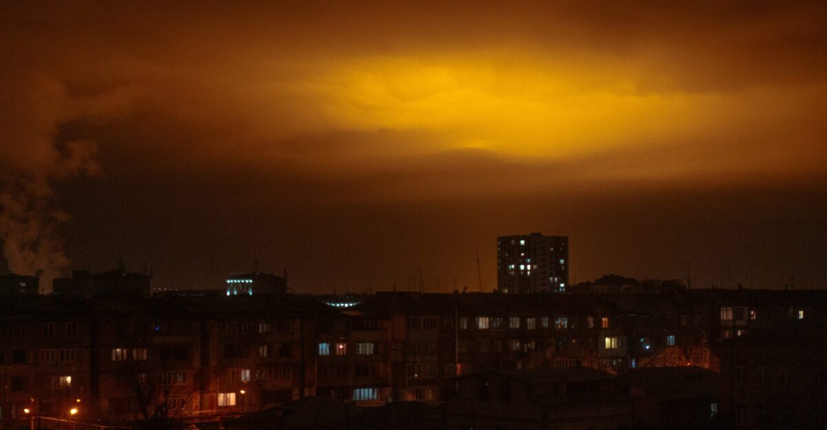a city at night with smoke coming out of the stacks