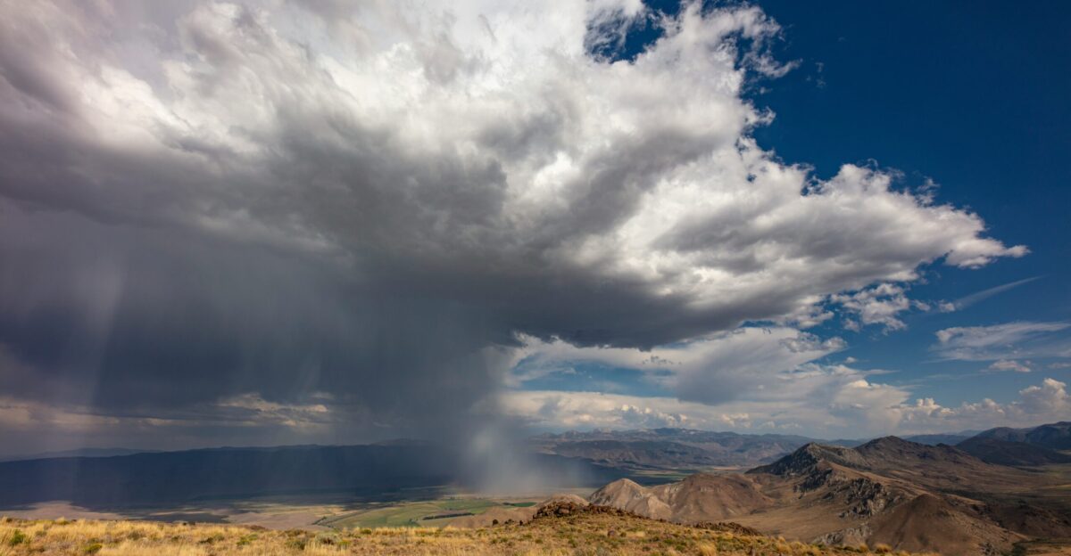 A large cloud is in the sky over a field