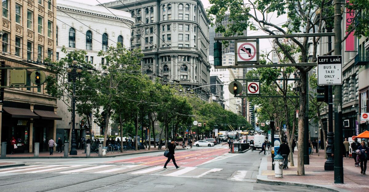 A bustling downtown San Francisco street with historic buildings and pedestrians crossing