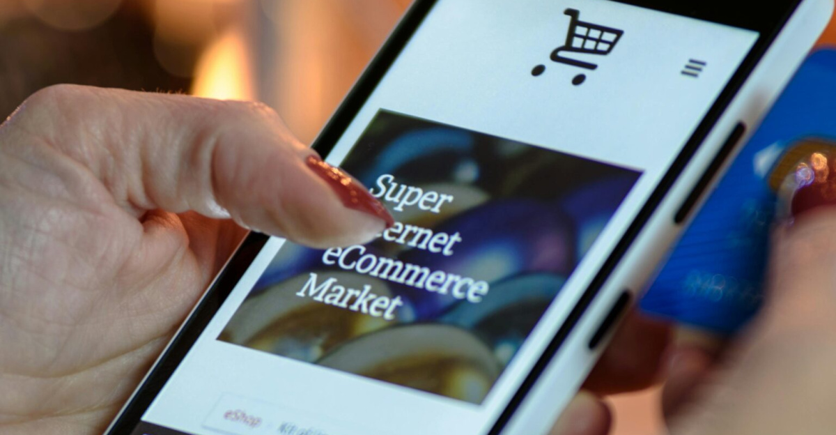 Woman using smartphone for online shopping with credit card in hand, festive background lighting.