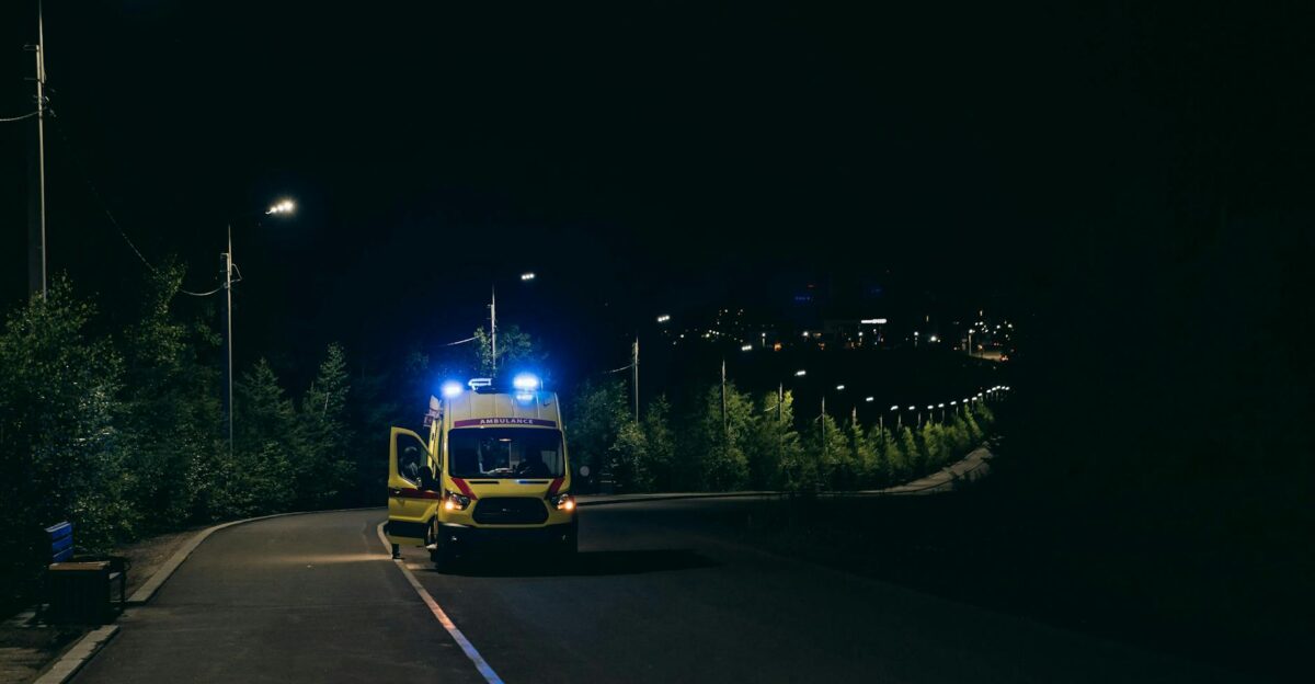 Ambulance with flashing lights on a rural road at night ready for emergency response