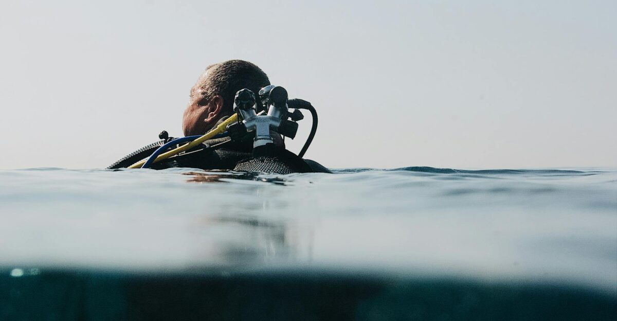A scuba diver floats at the water s surface in an over-under shot capturing ocean exploration