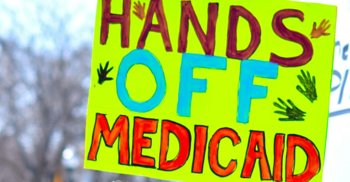 A diverse group protests to protect Medicaid, holding signs advocating healthcare rights.
