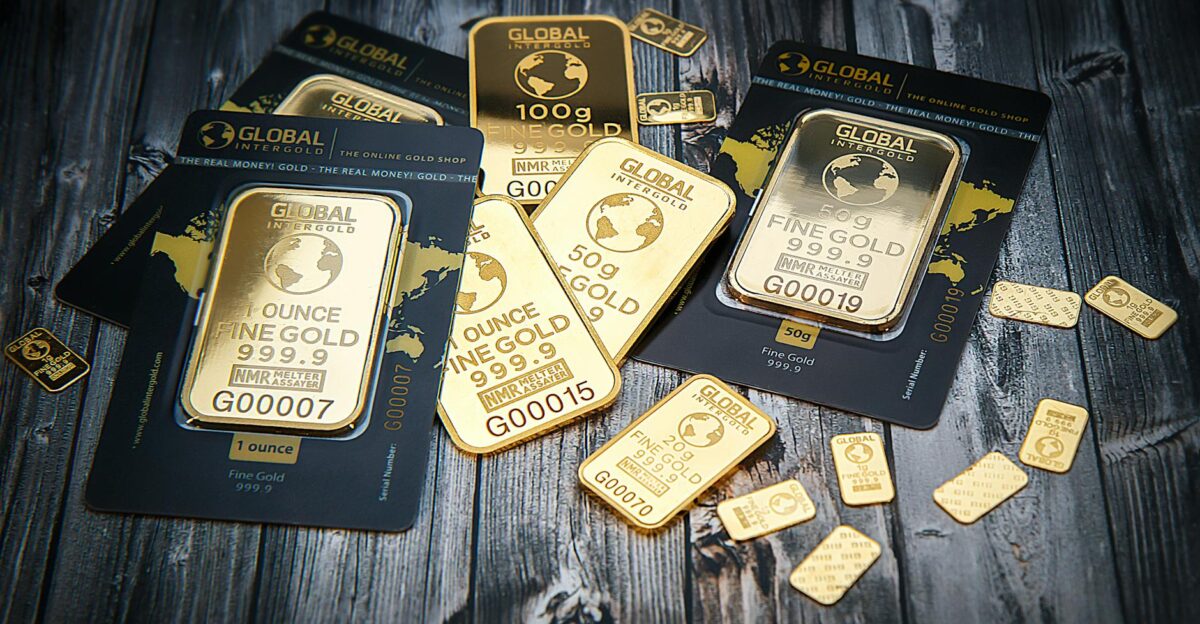 A collection of fine gold bars displayed on a textured wooden surface
