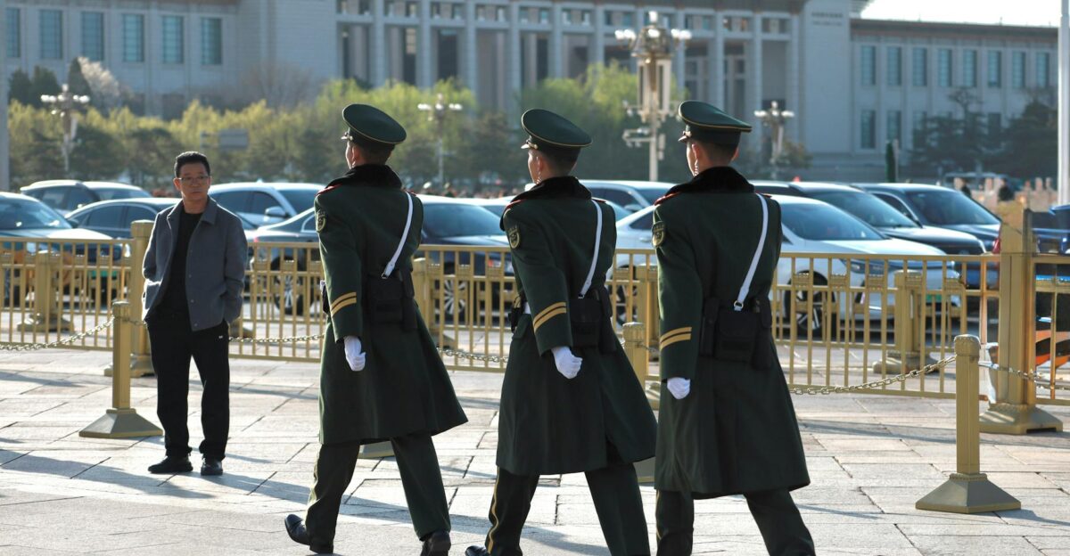 Uniformed guards march in formation outside a grand museum building on a sunny day