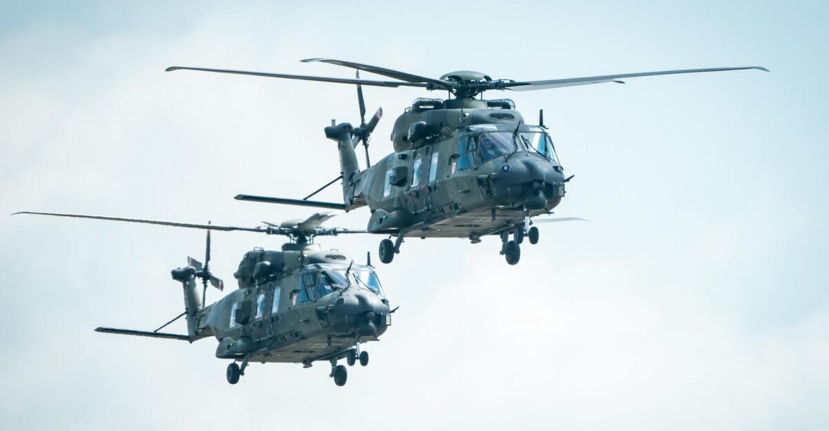 Two military helicopters flying in the sky showcasing aviation technology
