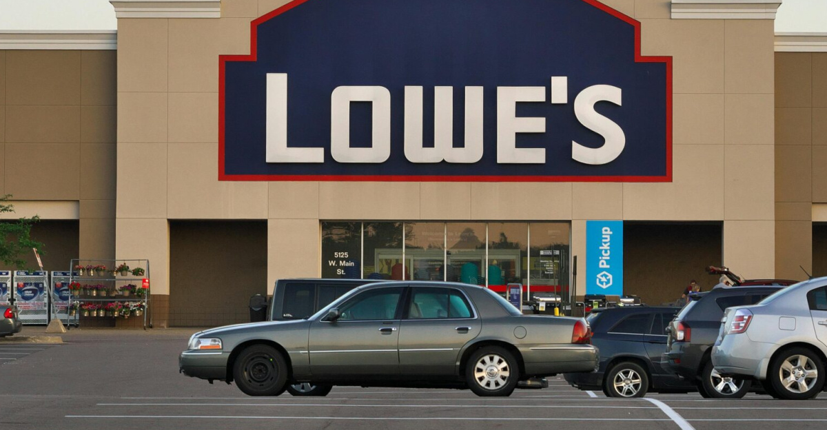 Front view of a Lowe's store entrance with parked cars in the lot during the day.