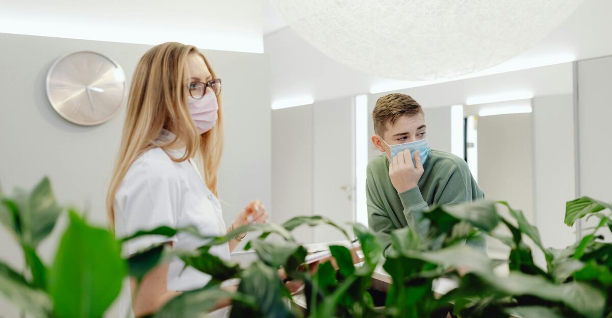 Man and woman wearing face masks in a clinic discussing at a counter indoors