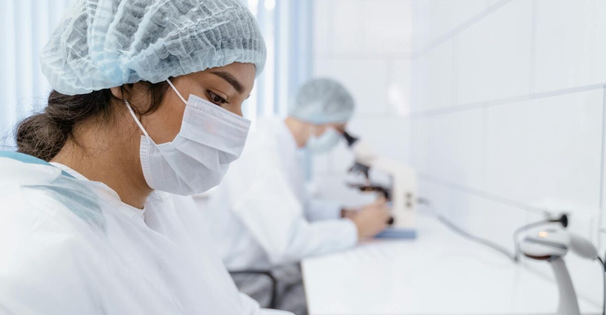 Two lab technicians wearing masks and protective gear working in a laboratory setting