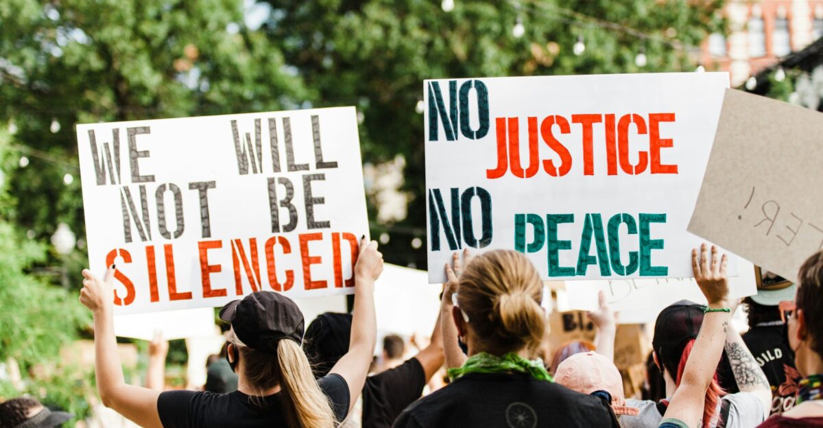 woman in black shirt holding white and green signage
