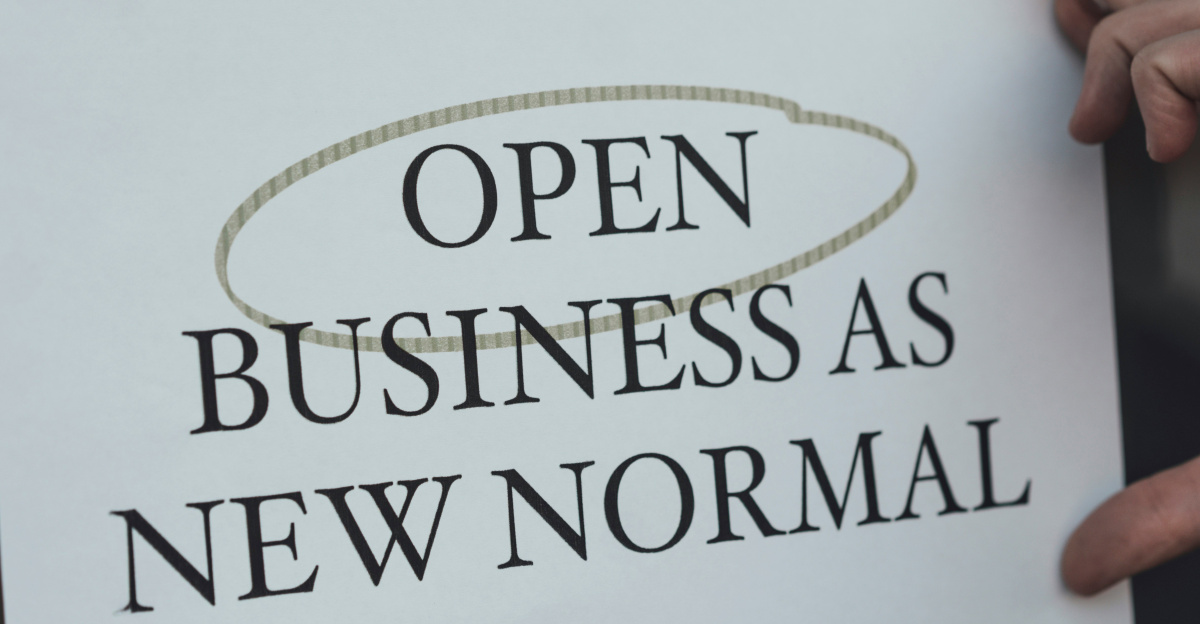 a person holding a sign that says open business as new normal