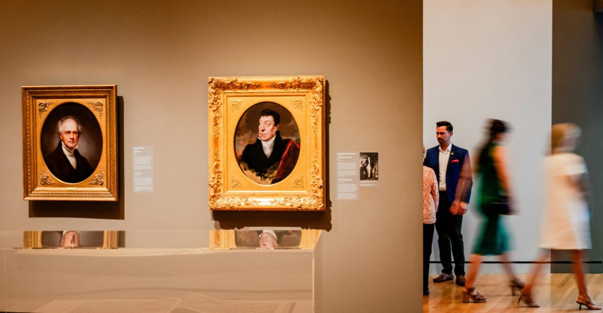 a group of people looking at paintings on display